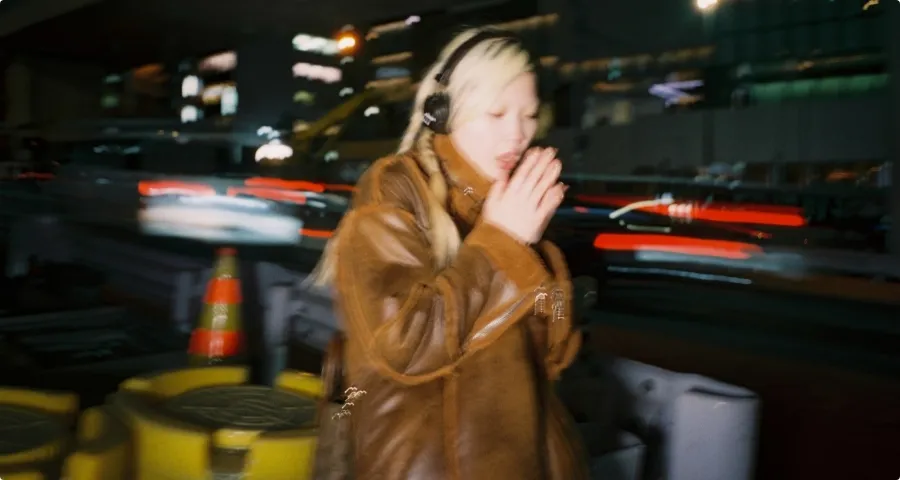 夜の都会の光跡を背景に佇む女性
